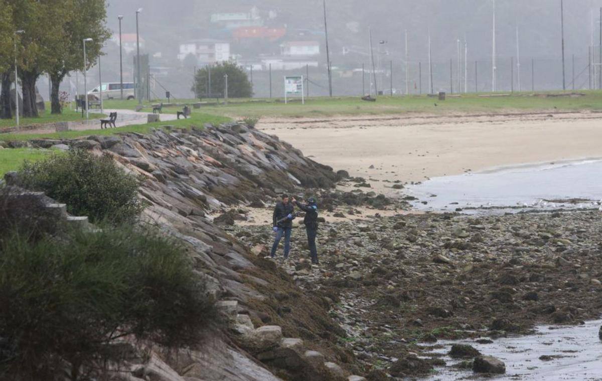 Miembros de las fuerzas del orden junto al cadáver de la mujer en el muelle de Domaio y el coche del accidente tras subirlo del mar.   | // S.Á.