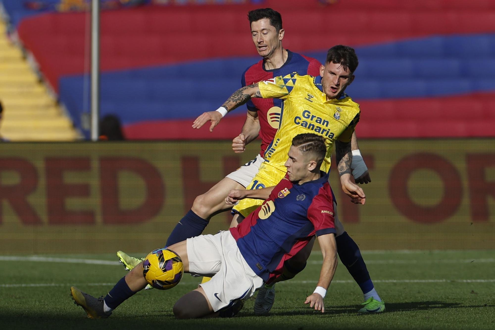 BARCELONA, 30/11/2024.- El centrocampista del FC Barcelona Fermín (frente) y el delantero polaco Robert Lewandowski (atrás) luchan por el balón con el defensa Viti (c) de la UD Las Palmas durante su partido de LaLiga en el Estadio Olímpico Lluís Companys en Barcelona este sábado. EFE/Alberto Estevez